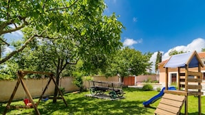 A backyard with a swing set, a slide, and a wooden playhouse. - Charming Villa With Private Swimming Pool (Zminj)