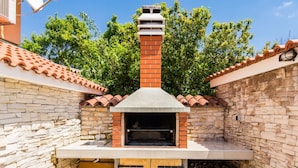 A stone-built outdoor kitchen with a chimney, a wooden door, and a tiled roof. - Charming Villa With Private Swimming Pool (Zminj)