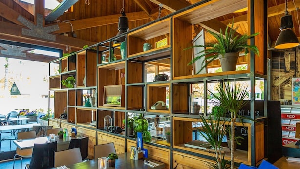 A restaurant with wooden shelves and tables, featuring various items like plants and kitchenware. - Comfortable Chalet Near Park De Veluwe (Otterlo)