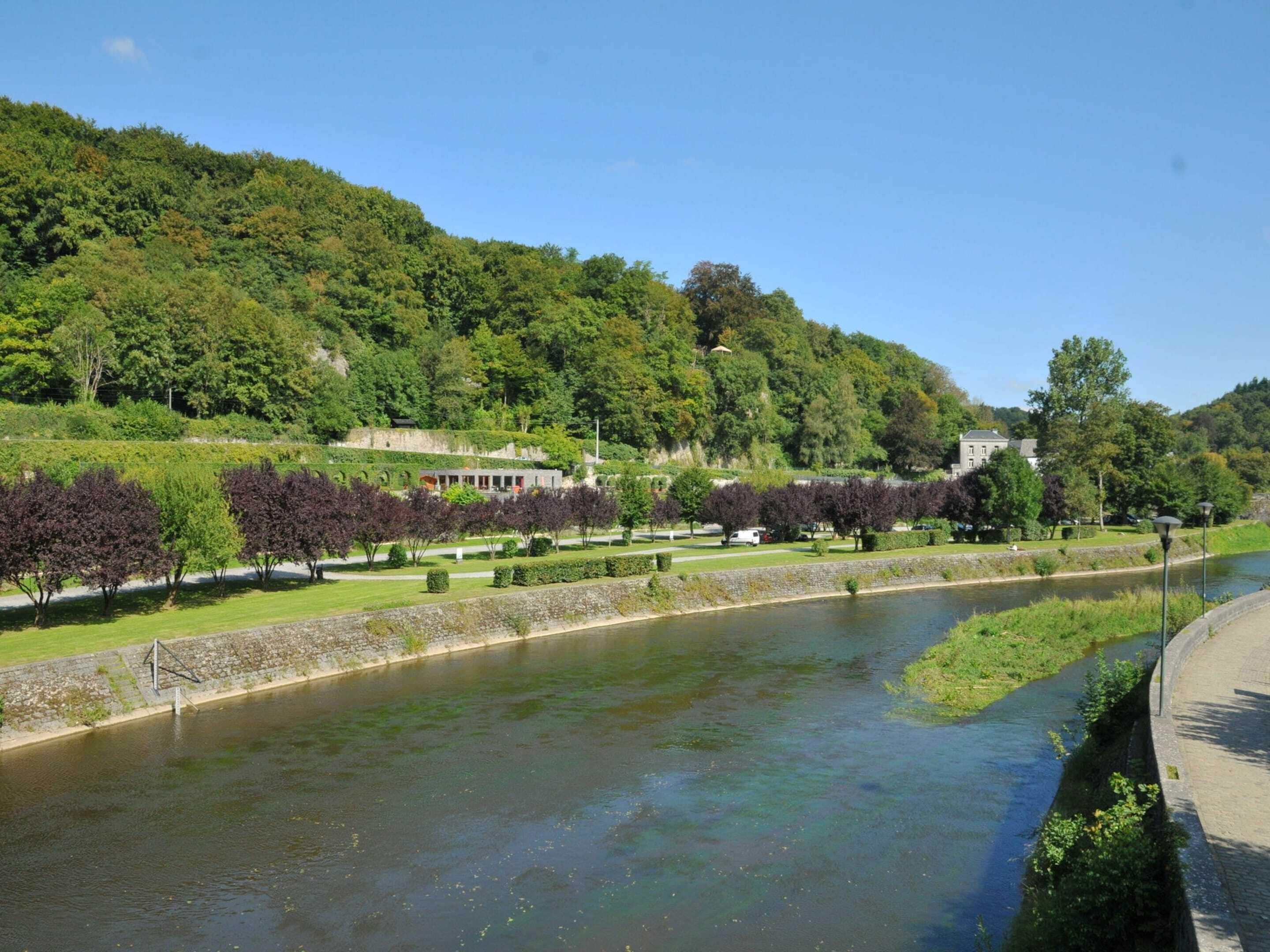 A river with a stone wall and trees along the banks.