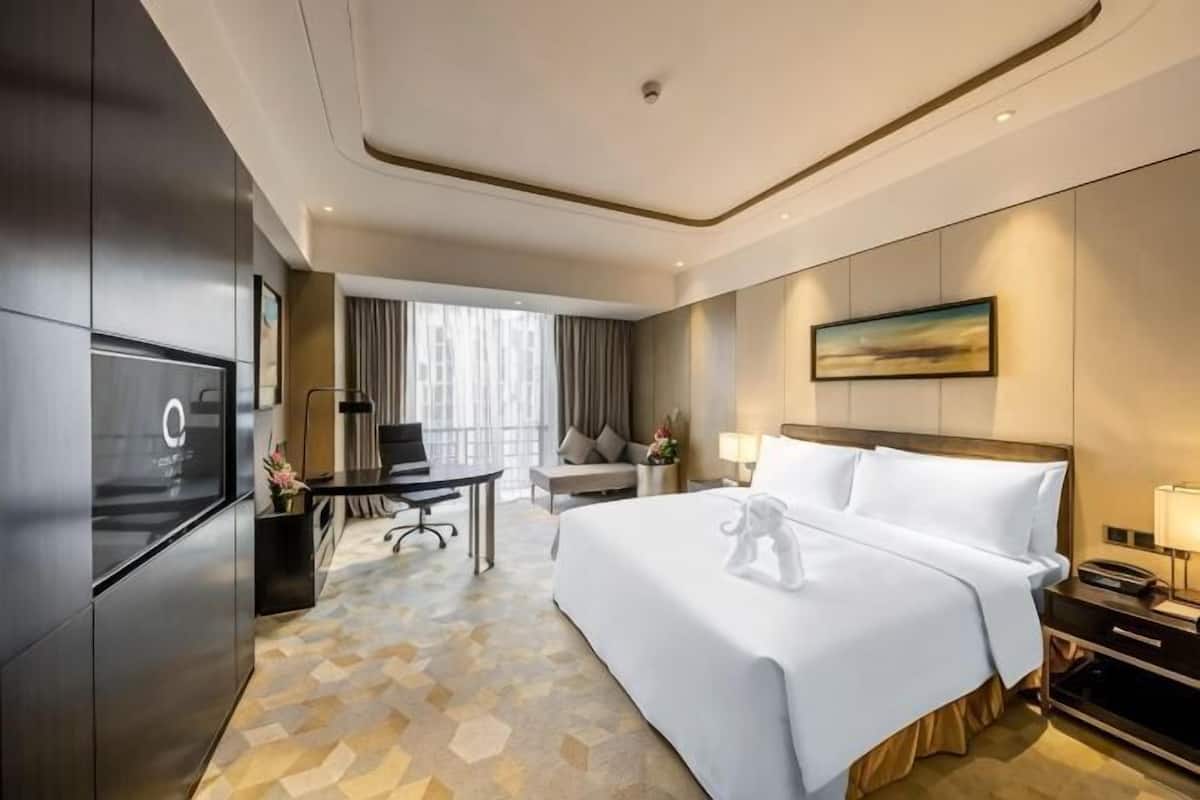 Ein Hotelzimmer mit Bett, Schreibtisch, Fernseher und Blick auf die Stadt.