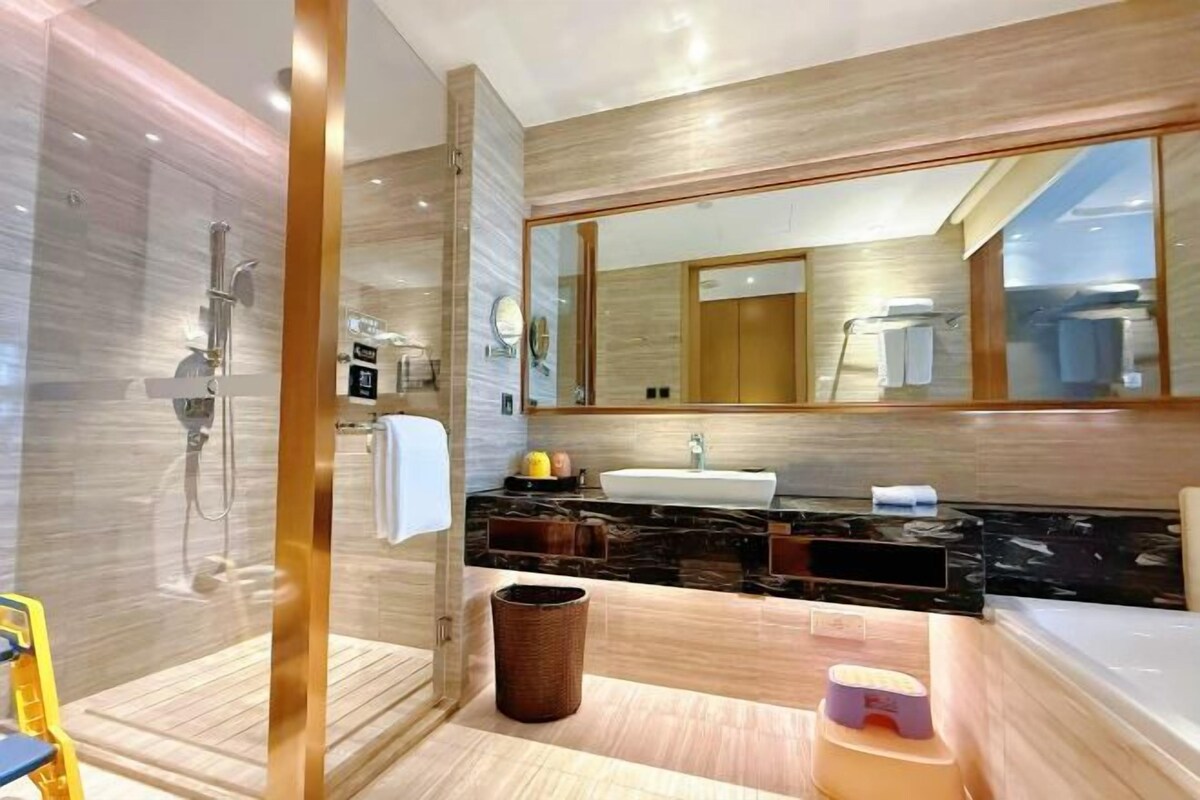 Un bagno moderno con doccia vetro, uno specchio grande, un lavandino e una vasca da bagno.