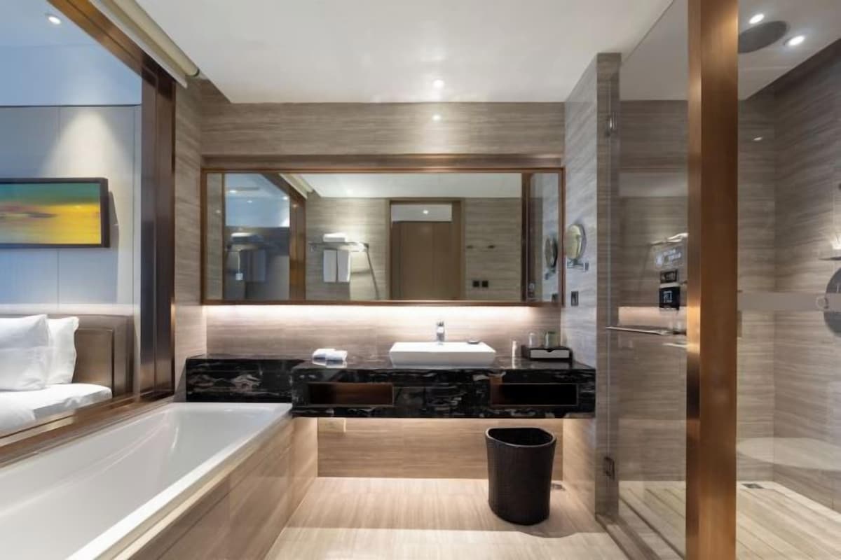 Un bagno moderno con uno specchio grande, una vasca e un mobile lavabo.