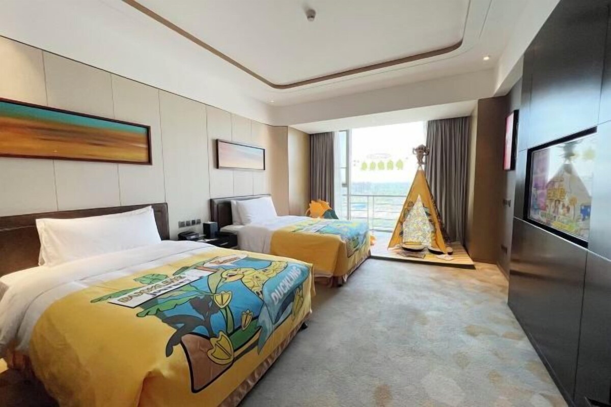 Una camera d'albergo con due letti, un'ampia finestra vista, una TV e un minibar.