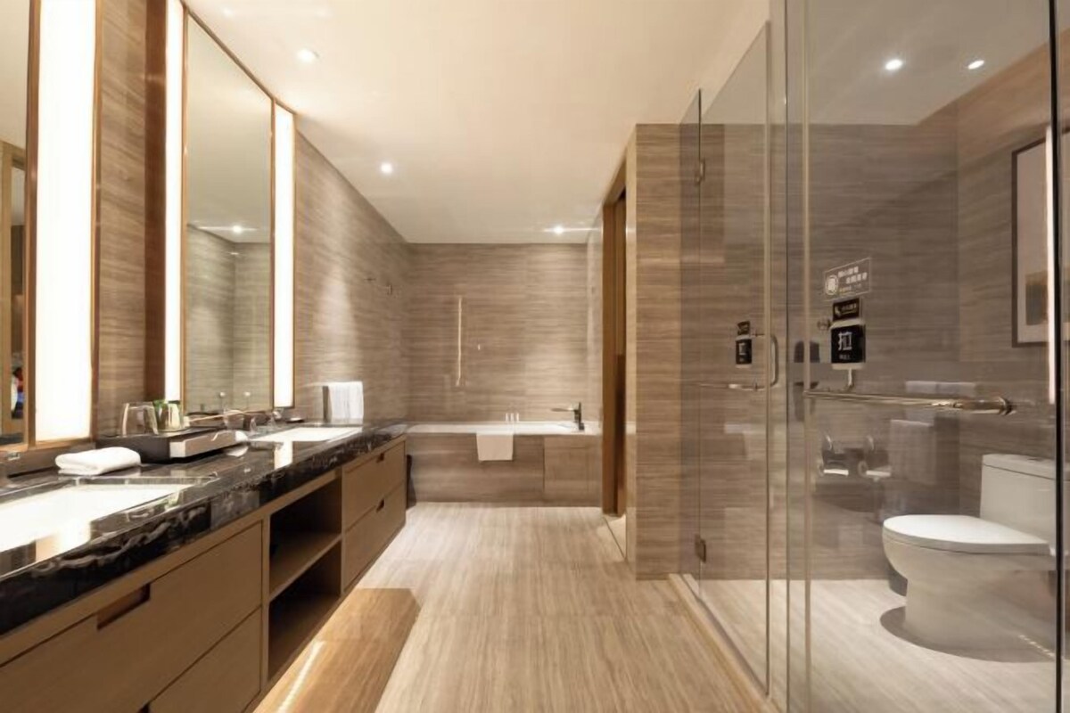 Un bagno moderno con box doccia in vetro, uno specchio grande e un mobile vanitario con piano in marmo.