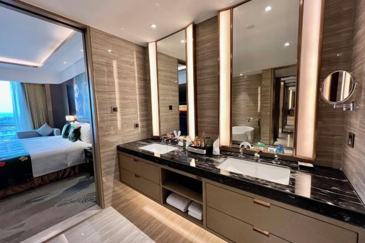 Un bagno moderno con uno specchio grande, due lavandini e un cabina armadio.