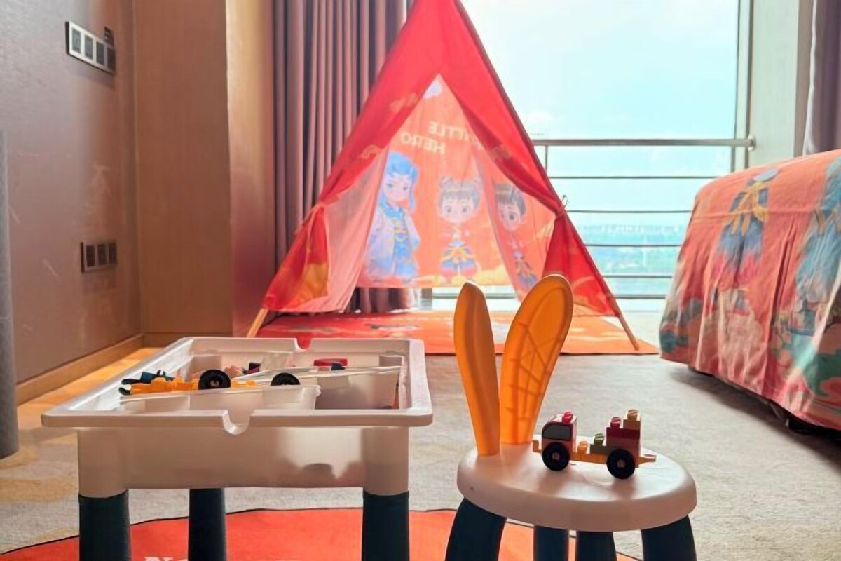 Un'area giochi per bambini con una tenda da gioco, un'automobile giocattolo e un tavolo giochi pieno di giocattoli.