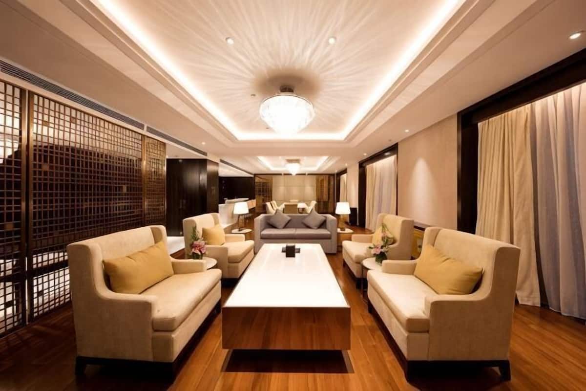 Ein modernes Hotelzimmer mit einer zentralen Sitzecke, einem großen Kronleuchter und einem Holzboden.