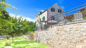 A stone building with a balcony, surrounded by a well-maintained lawn and trees. - Villa in Sumartin Near Beach & Private Pool (Selca)