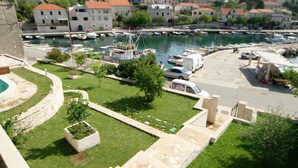 A marina with boats, a parking area, and a view of a town with historic buildings. - Villa in Sumartin Near Beach & Private Pool (Selca)