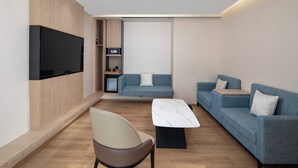 A modern living room with a flat-screen TV mounted on the wall, a sofa, a coffee table, and a chair. - Fairfield by Marriott Beijing Haidian (Beijing)