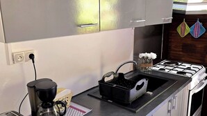 A kitchen with a gas stove, a coffee maker, a toaster, and a sink. - Bungalow 2 bdrms in quiet flowered park 3 min from beach and 5 min from town (Deshaies)
