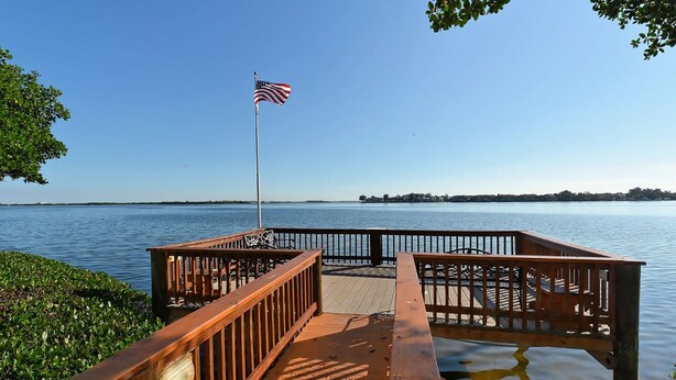 A wooden dock with a flagpole, leading to a calm body of water. - Escape to Classic Anna Maria Island Charm (Bradenton Beach)