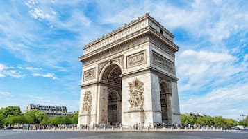 Un monumento grande e histórico con intrincados grabados y estatuas, rodeado de gente.