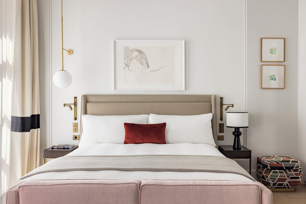 A neatly arranged hotel room with a bed, bedside tables, a lamp, and artwork on the wall.