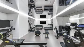 Un gimnasio moderno con diversos equipos de ejercicio, incluyendo cintas de correr, máquinas de pesas y pesas libres.