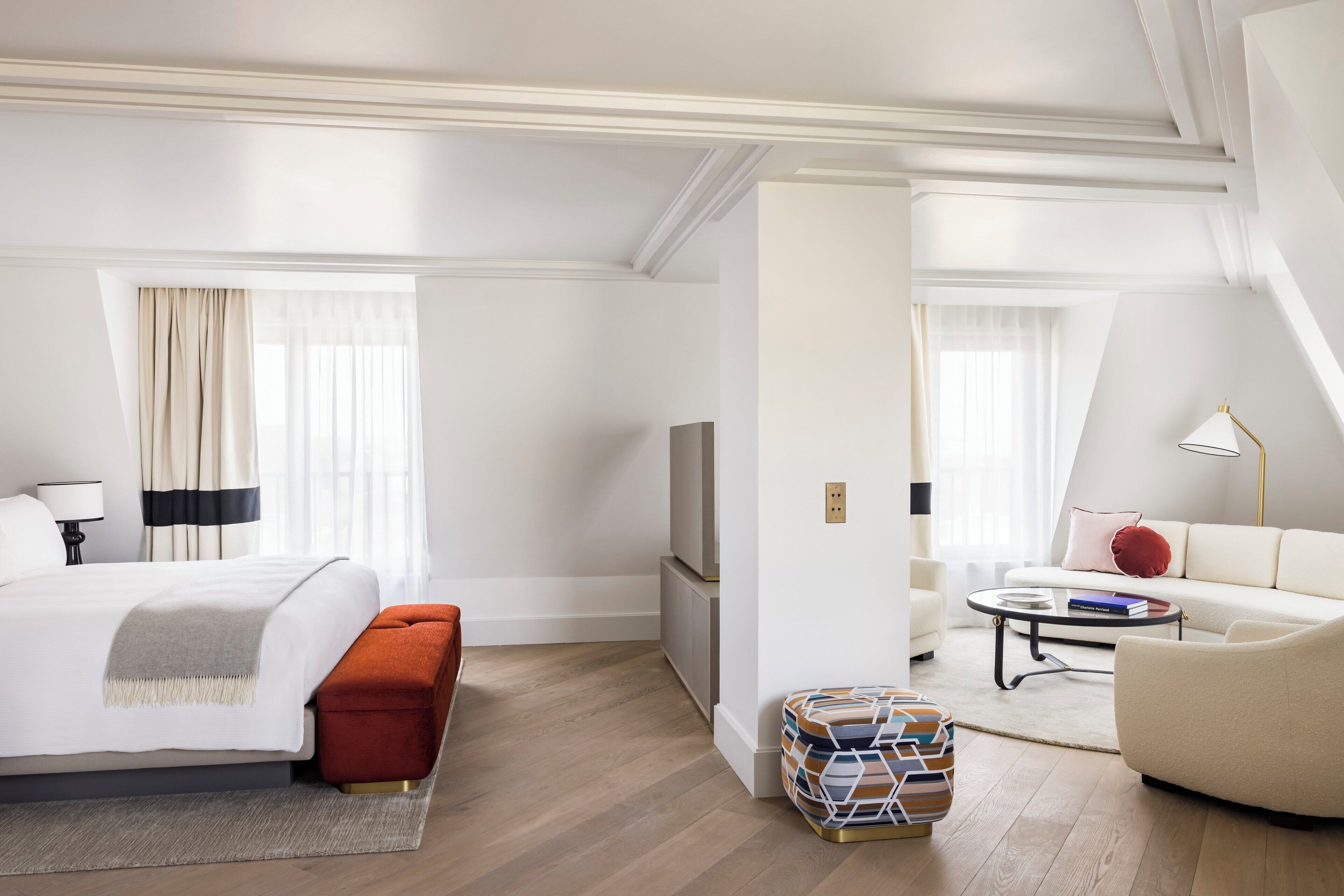 A hotel room with a bed, a sofa, a TV, a coffee table, and a small side table.