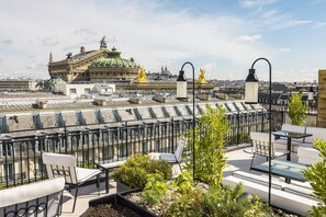 A rooftop terrace with outdoor seating and a view of a historic building with a green dome. - Kimpton St Honore Paris by IHG (Paris)