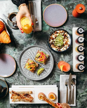 A breakfast setting with croissants, toast with avocado and vegetables, a bowl of yogurt with fruit, and a variety of drinks. - Kimpton St Honore Paris by IHG (Paris)