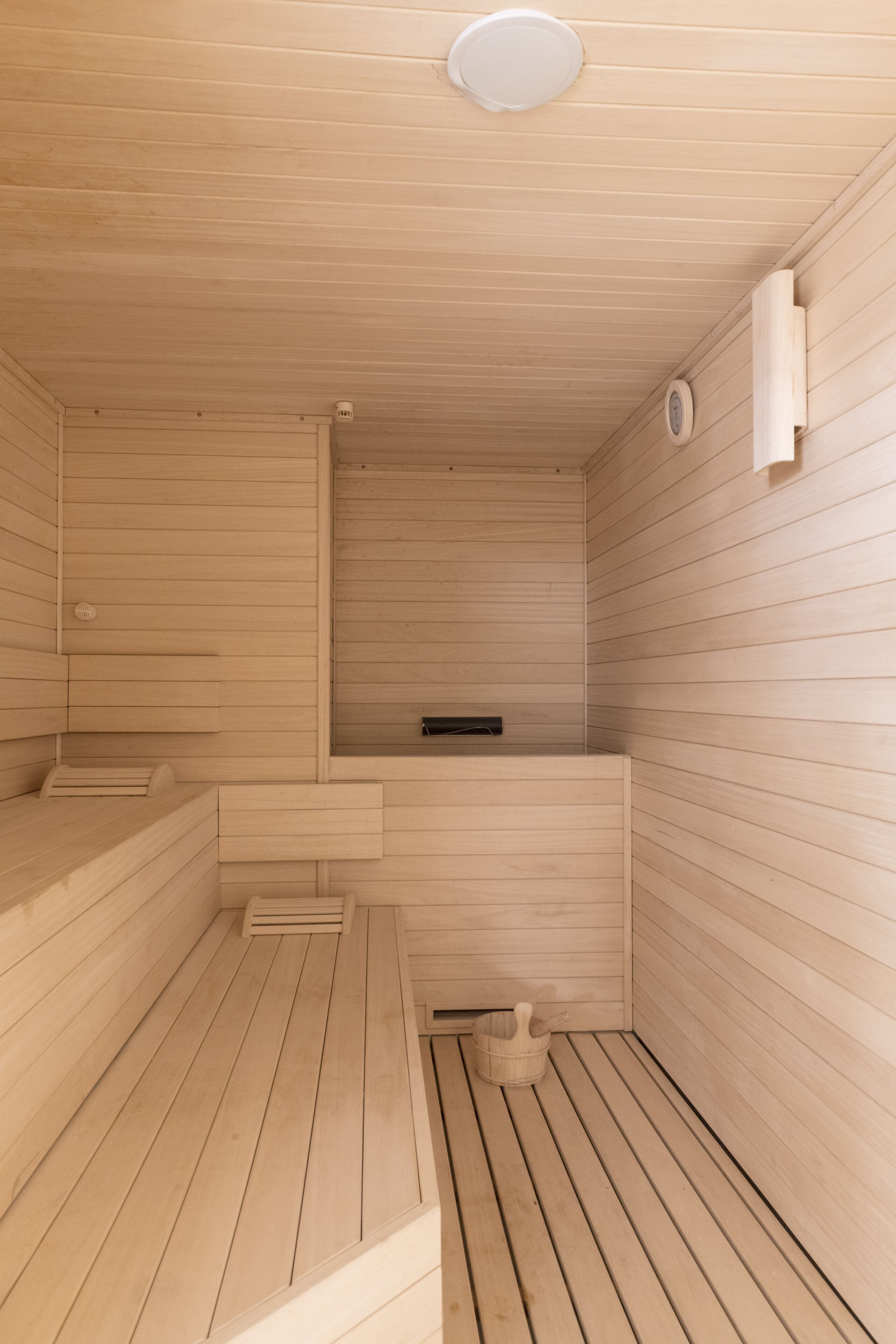 Una sauna de madera con bancos y un asiento tipo banco.