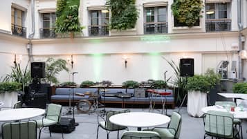 Un espace extérieur aménagé avec un canapé, des tables, des chaises et des instruments de musique.