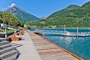 A wooden pier extending into a lake with a mountain backdrop.