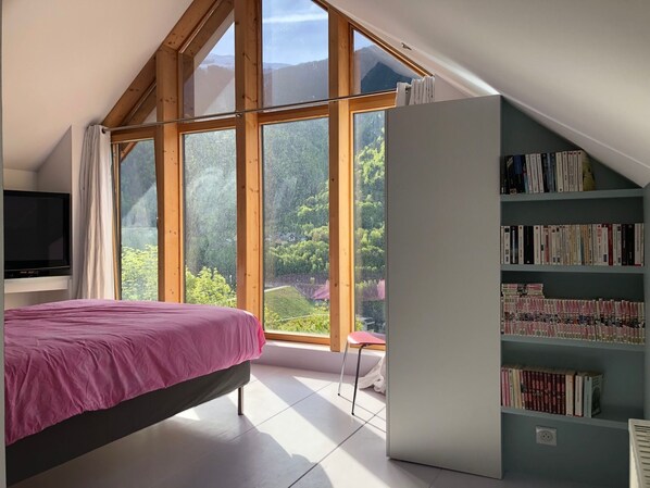A bedroom with a bed, a bookshelf, and a TV.