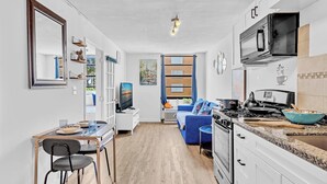 Una cocina moderna con estufa, microondas y fregadero. Hay un comedor con mesa y sillas.