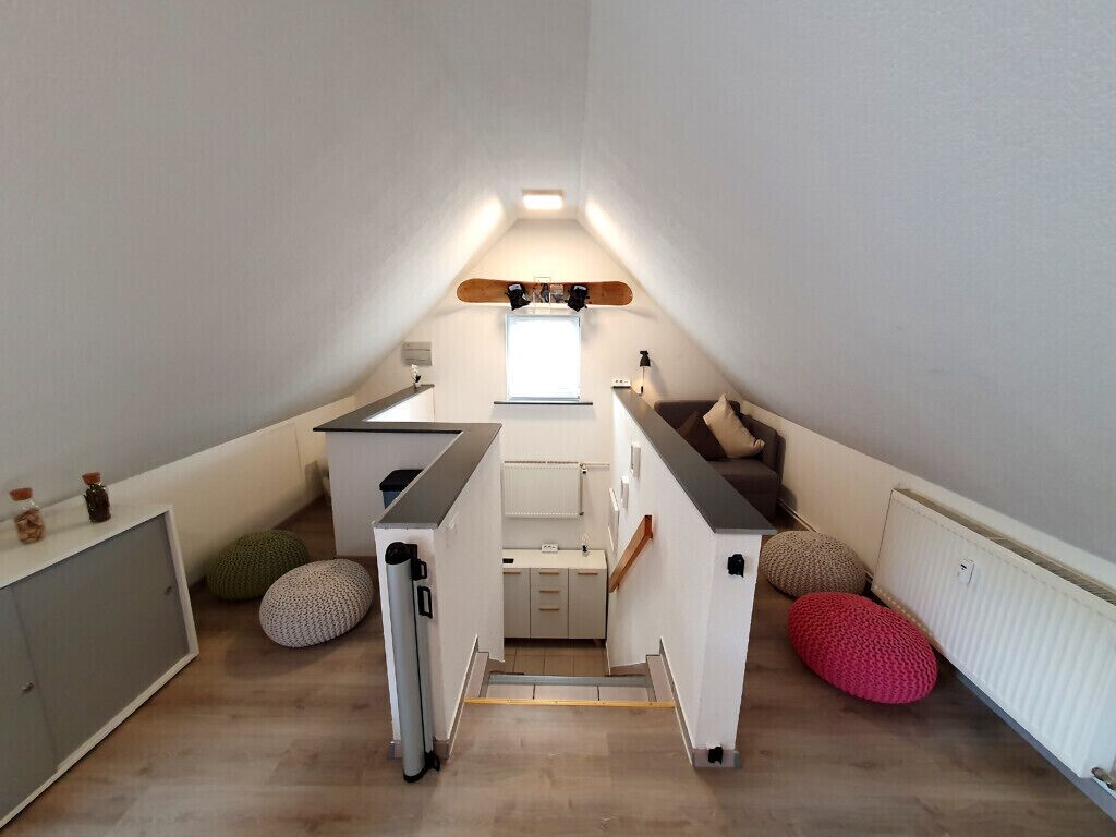Une petite chambre mansardée comprenant un coin cuisine, une fenêtre et un plafond en pente.