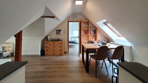Et rummeligt loftsværelse med spiseplads, møbler af træ og et ovenlysvindue.