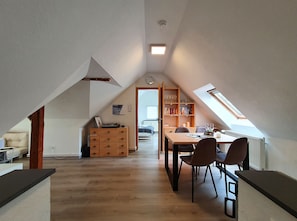A spacious attic room with a dining area, wooden furniture, and a skylight.