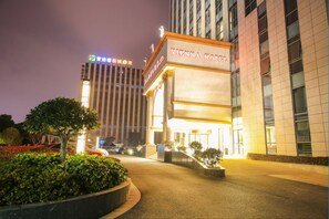 A hotel entrance with a sign reading 'VIENNA HOTEL' and a modern building in the background.