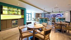 A modern bar area with a variety of beverages, wooden tables and chairs, and a visible exit sign. - Premier Inn Darlington Town Centre Hotel (Darlington)