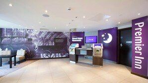 A hotel lobby with a check-in counter, a digital display, and a large wall mural. - Premier Inn Darlington Town Centre Hotel (Darlington)