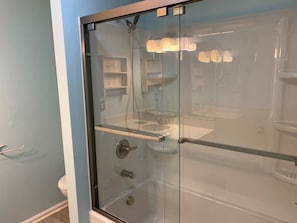 Une douche fermée par des parois de verre, avec un lavabo et un porte-serviettes visibles à l’intérieur.