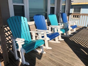 A deck with several Adirondack chairs and small tables, likely for outdoor dining or relaxation.
