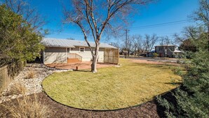 A residential property with a fenced yard, a small house with a covered porch, and a clear blue sky.