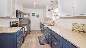 A modern kitchen with white cabinets, stainless steel appliances, and a blue accent wall.