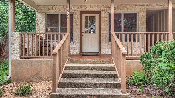 A stone house with a front porch, a front door, and a staircase leading to the entrance.