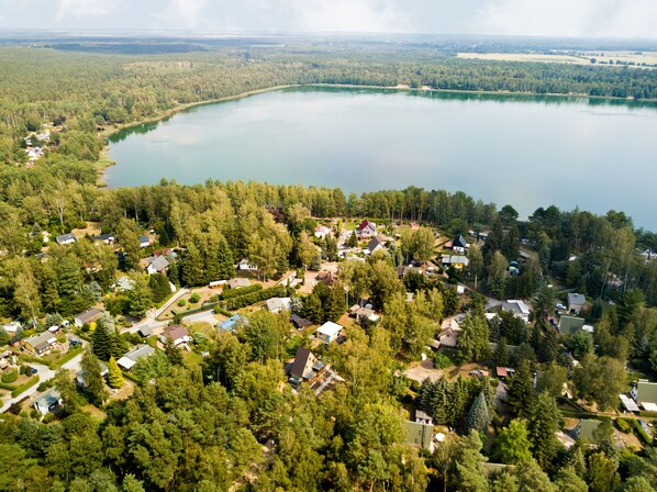 Luchtbeeld van een woongebied aan een meer, met huizen omringd door dicht bos.