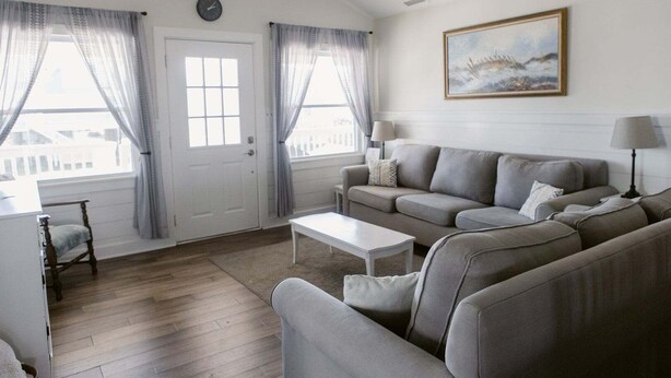 A living room with a sofa, a coffee table, a lamp, and a painting on the wall. - Discover coastal charm at Holden Pattern, a spacious 4BR home in Holden Beach. (Holden Beach)