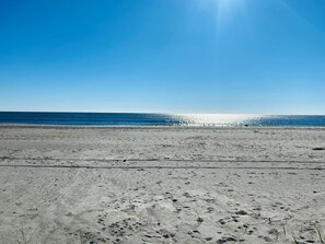 Enjoy a serene beach experience with expansive views of the ocean and a clear horizon.
