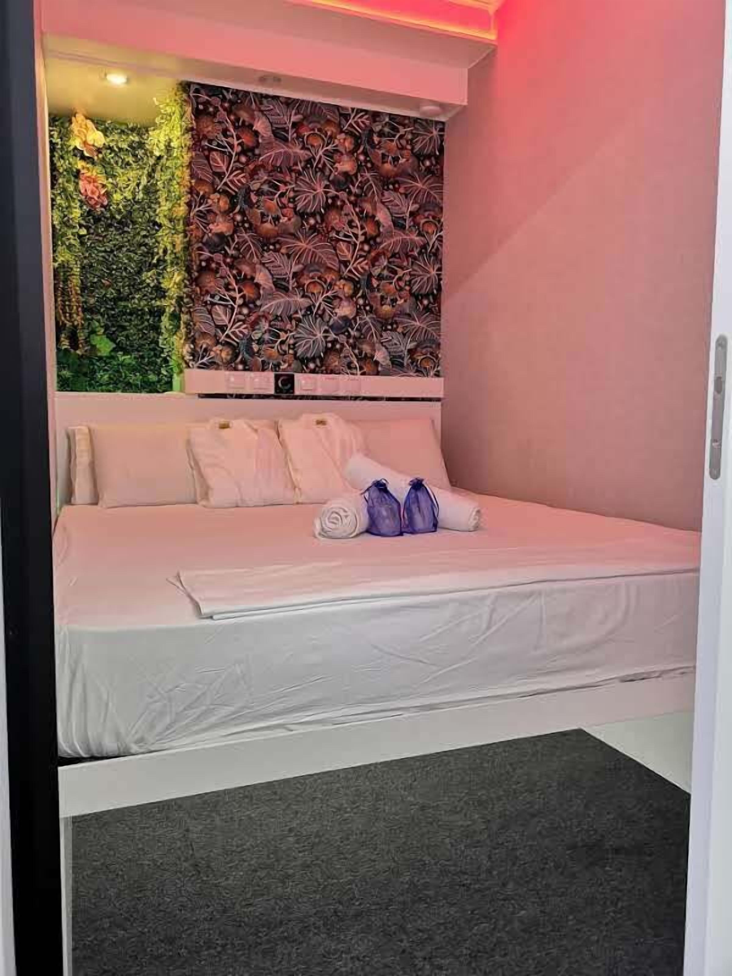 Een moderne slaapkamer met een bed, kussens en een muur met een bladmotief.