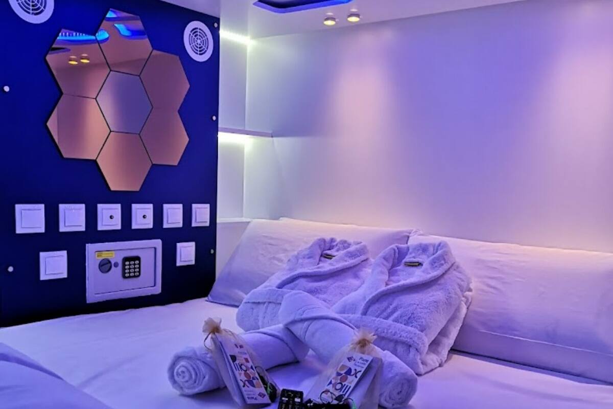 A modern hotel room with a bed, towels, and a control panel on the wall.