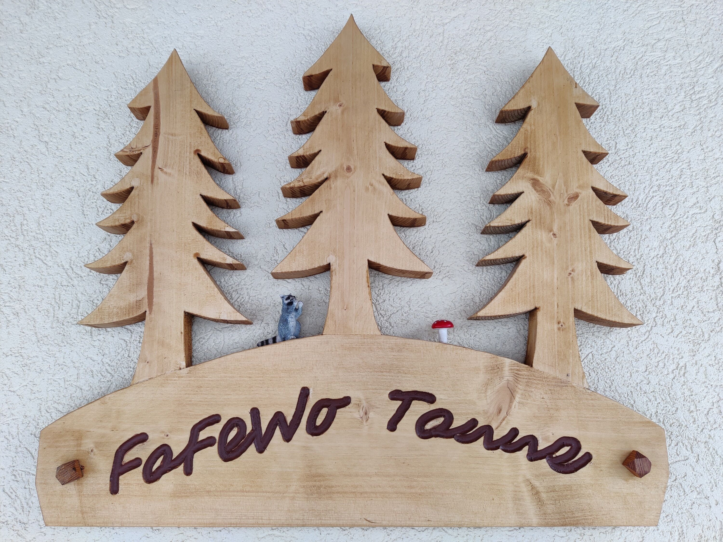 Une enseigne en bois représentant trois arbres stylisés, avec l’inscription « Fafowo Tanna ».