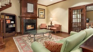 Una sala de estar con chimenea, una escalera, una estantería y un sofá verde.