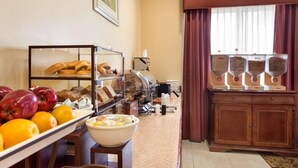 Un bufé de desayuno con frutas, pasteles y una estación de café.