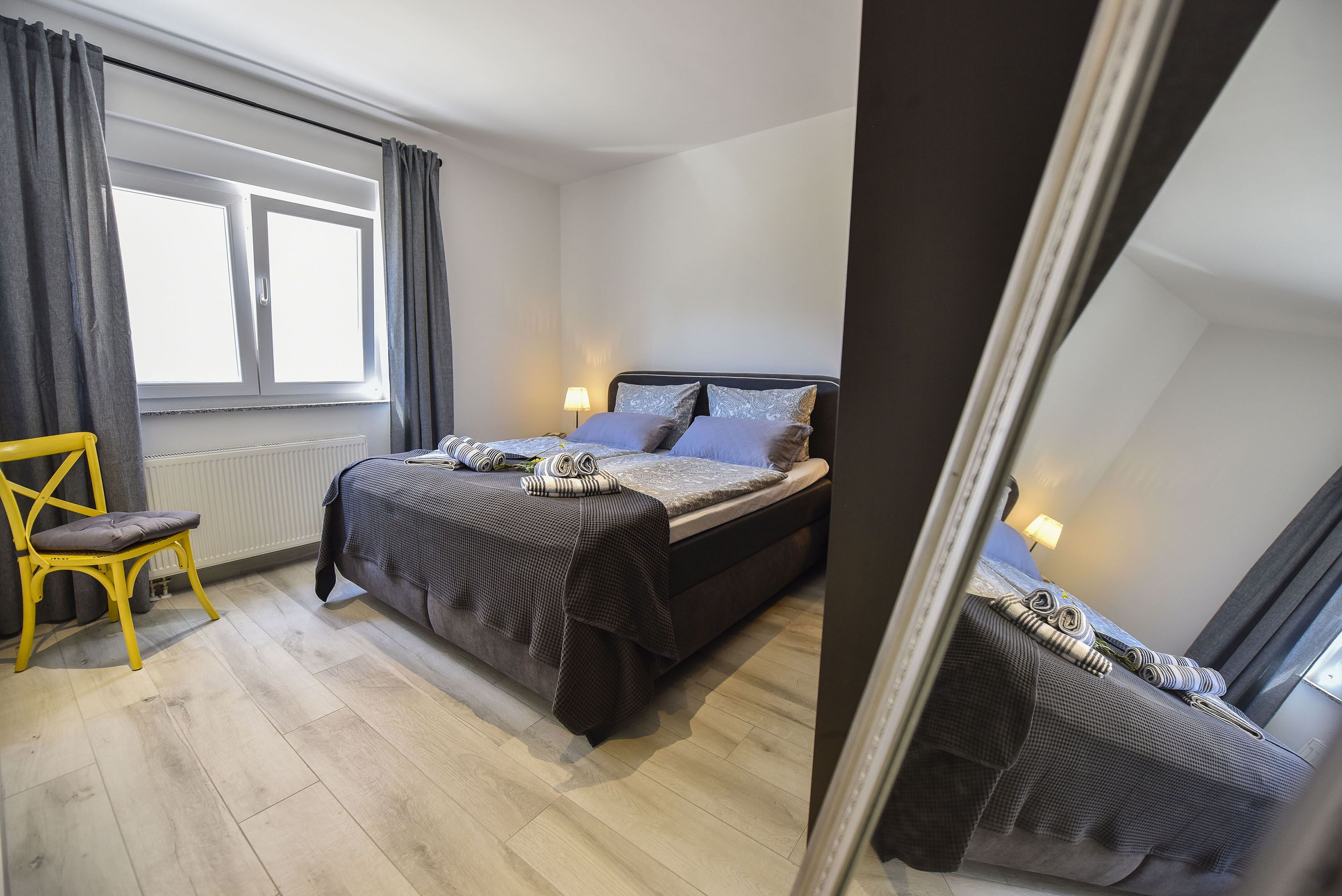 Ein Schlafzimmer mit Bett, Stuhl, Fenster und Lampe.