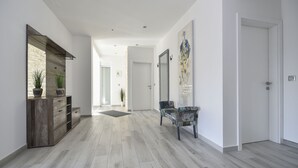 Un pasillo amplio con un armario de madera, un banco y una puerta que da a otra habitación.