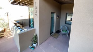 Zona exterior coberta amb terrassa, una porta, una cadira i plantes en testos.